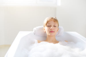 girl relaxing in bathtub on a light background